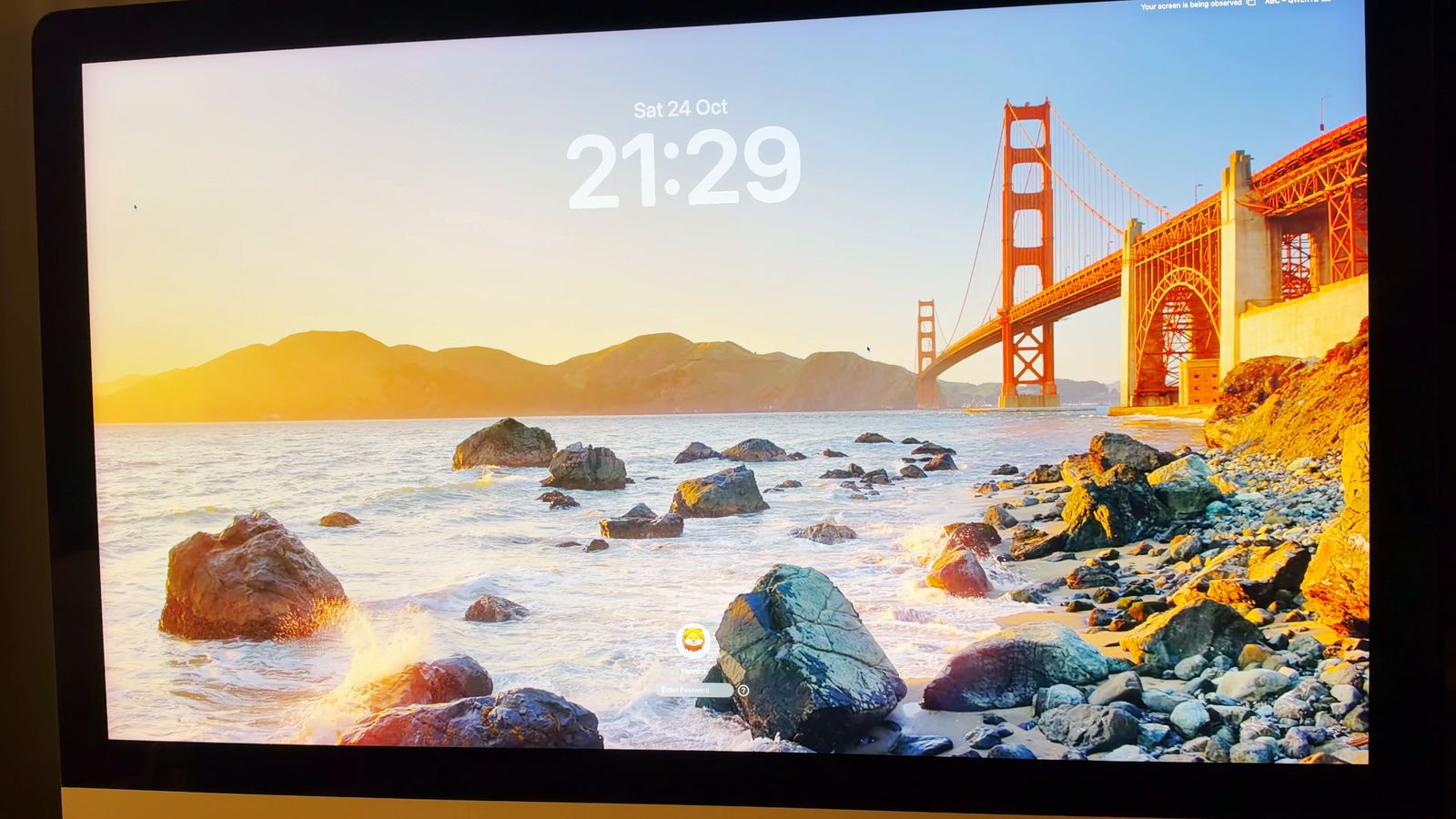 The iMac showing the Mac mini's lock screen: the date, the time 21:29 and the user picture at the bottom.